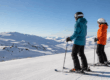 Dos esquiadores equipados en una pista de nieve con vistas a la montaña