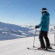 Dos esquiadores equipados en una pista de nieve con vistas a la montaña